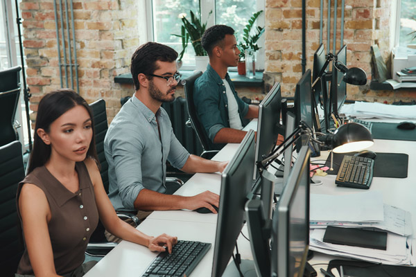 Group of People Sitting at a Long Desk with Computers for Business IT Services in Oceanside, CA
